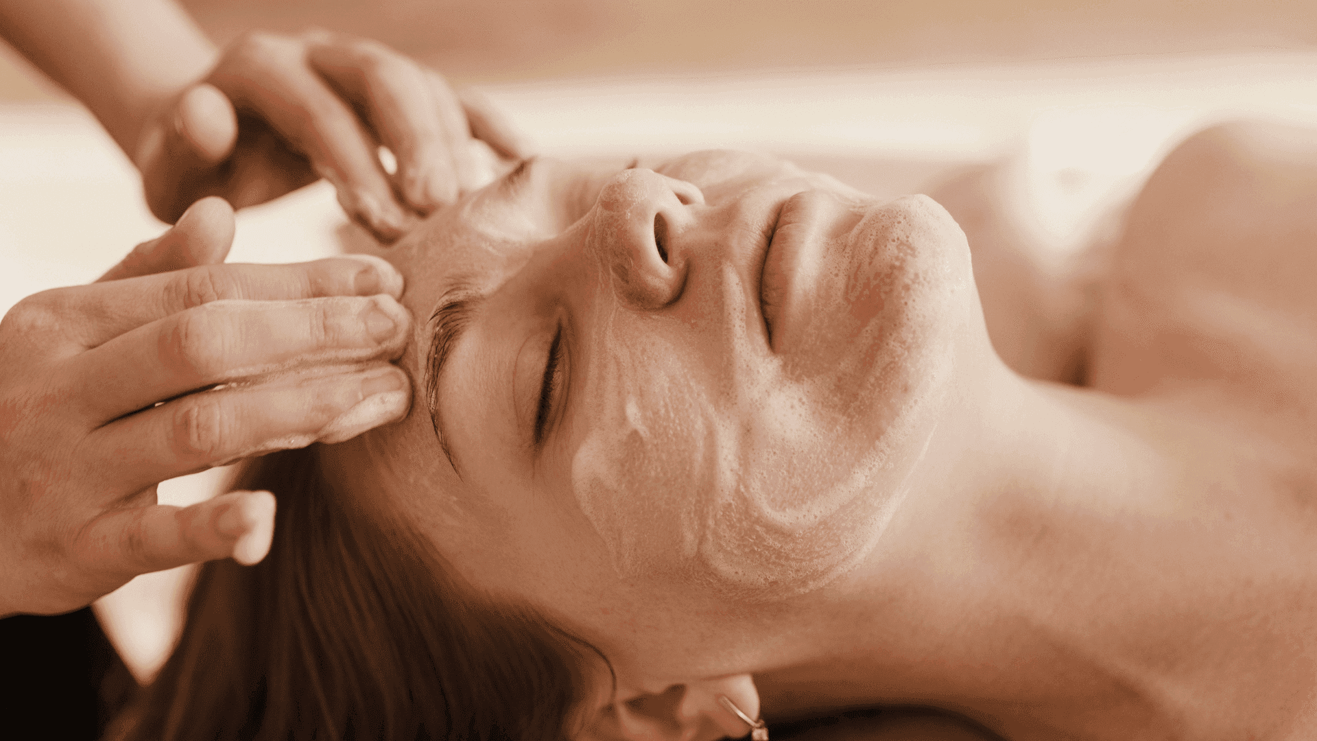 Person receiving a relaxing facial massage with a skin treatment mask applied.