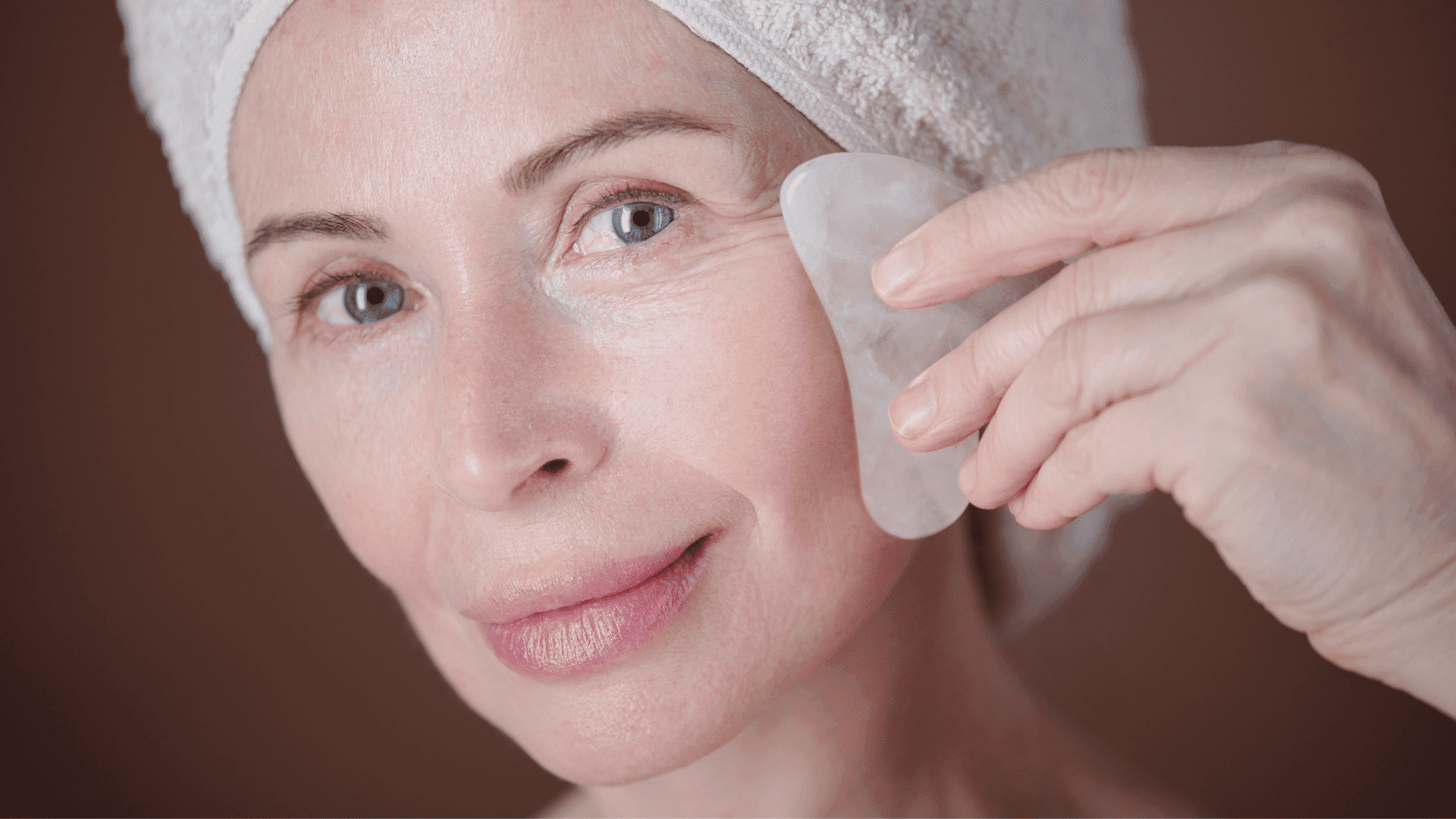 Woman using a gua sha stone on her face for skincare.
