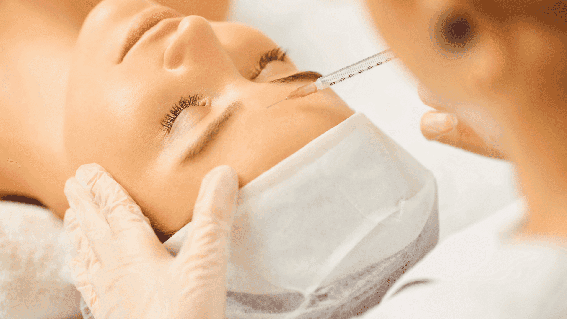Woman receiving a cosmetic injection in her forehead from a gloved professional.